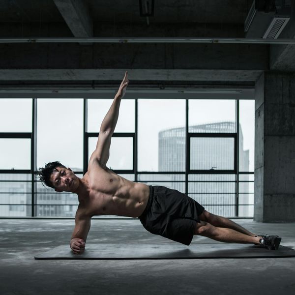 A focused man doing a plank variation, showcasing core stability.