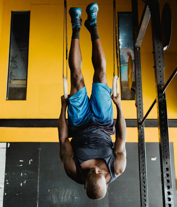 Man performing a controlled bodyweight exercise in a minimalist dark gym.